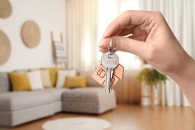 Woman with key in new modern apartment, closeup