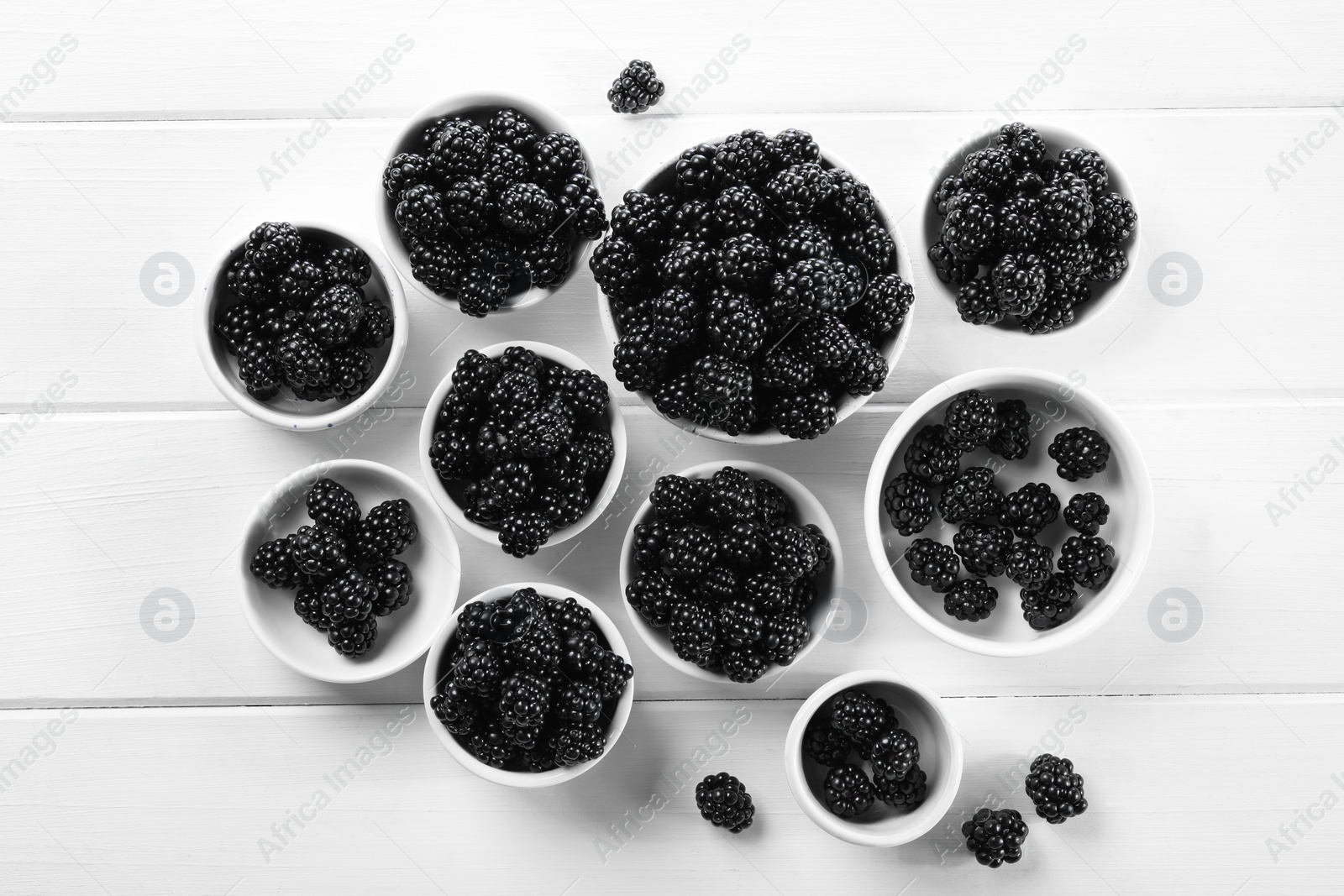 Photo of Ripe blackberries on white wooden table, flat lay