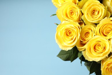 Beautiful bouquet of yellow roses on light blue background, closeup. Space for text