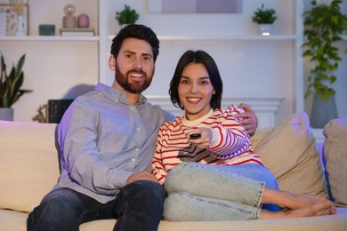 Photo of Happy couple watching TV on sofa at home