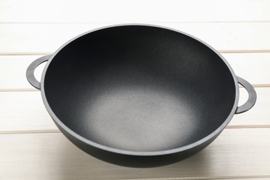 Empty iron wok on white wooden table. Chinese cookware