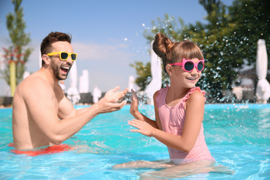 Father and daughter having fun in swimming pool. Family vacation