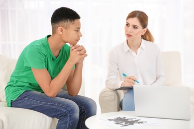 Female psychologist working with African American teenage boy in office