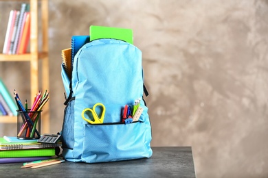 Photo of Backpack with school stationery on table indoors