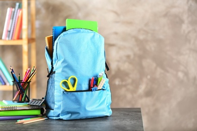 Backpack with school stationery on table indoors