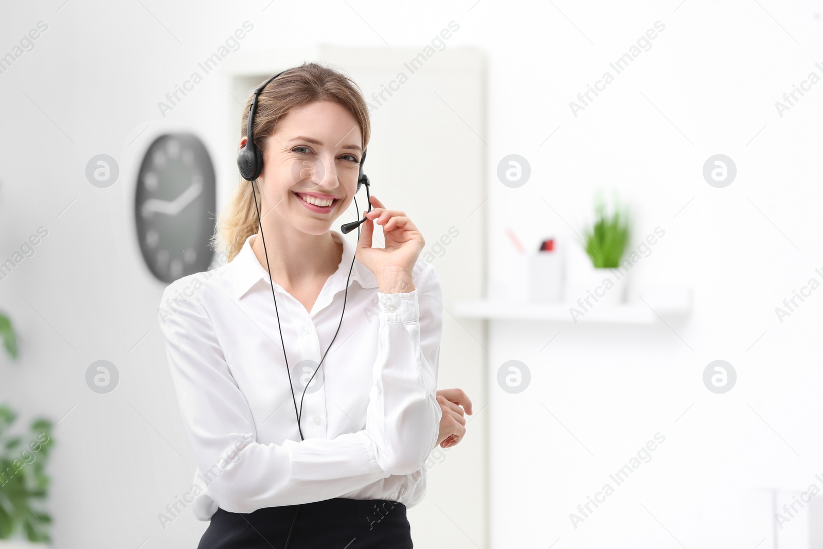 Photo of Young female receptionist with headset in office