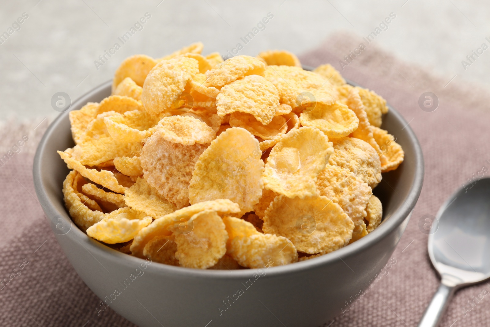 Photo of Bowl of sweet crispy corn flakes on kitchen towel, closeup. Breakfast cereal