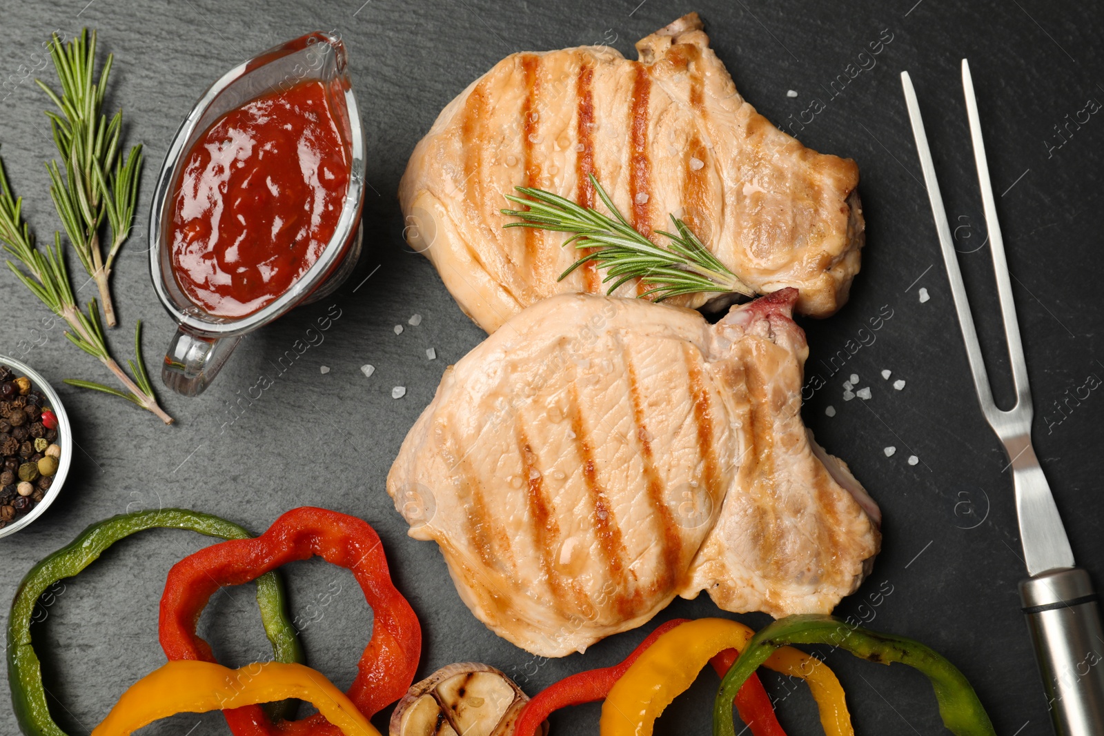 Photo of Grilled meat served with garnish and sauce on slate plate, top view