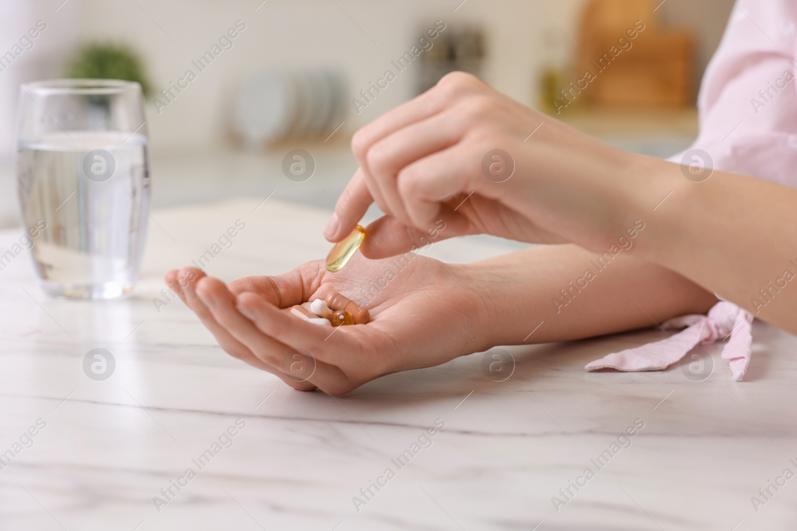 Photo of Woman with vitamin pills at table indoors, closeup