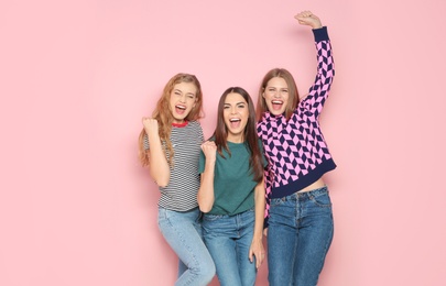 Young women celebrating victory on color background