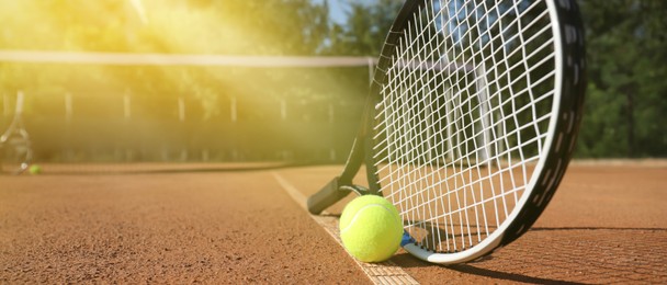 Tennis ball and racket on clay court, space for text. Banner design