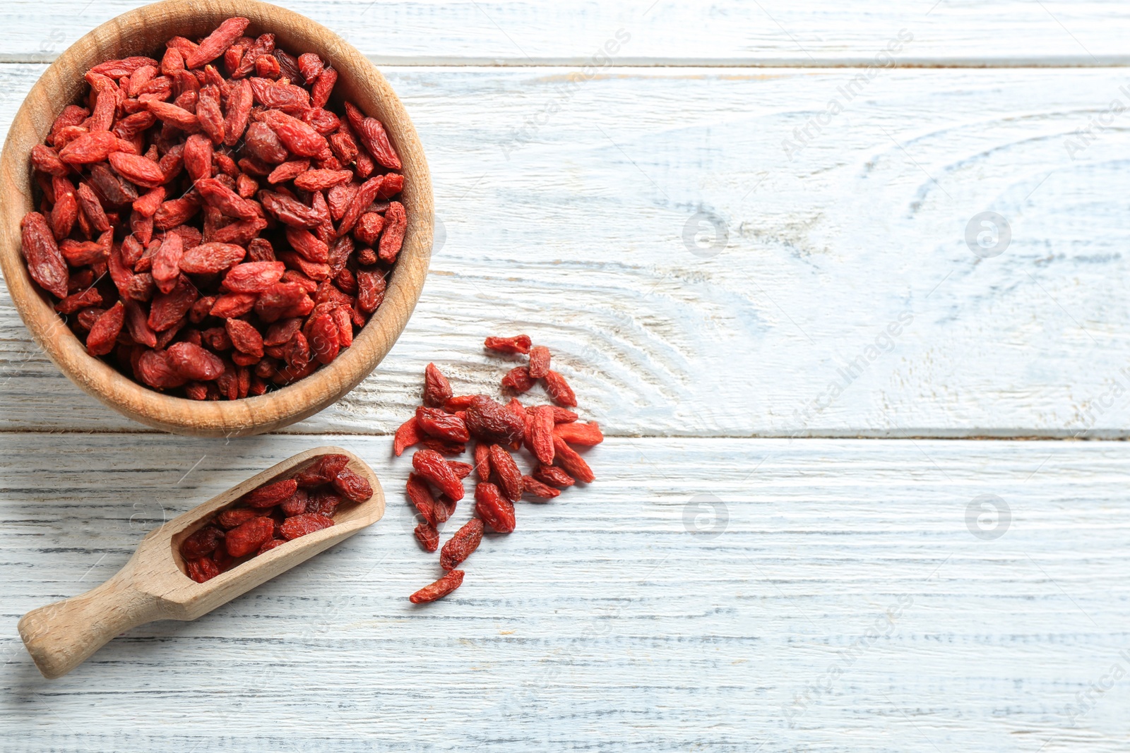 Photo of Flat lay composition with dried goji berries on white wooden table, space for text. Healthy superfood