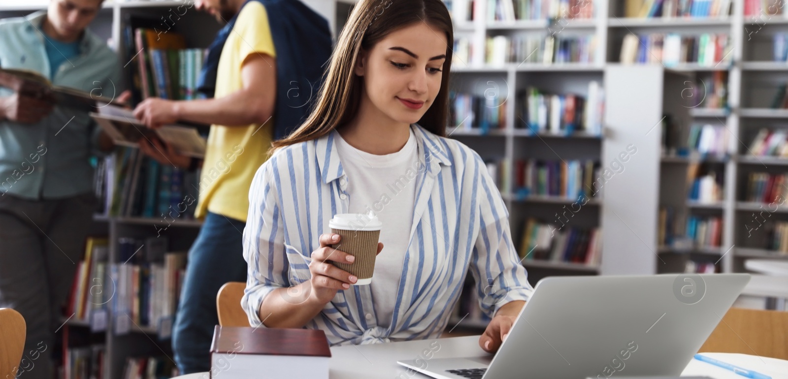 Image of Young student with laptop at table in modern library. Banner design