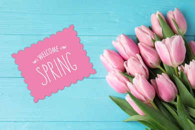 Beautiful pink tulips and greeting card on blue wooden background, top view. Hello spring