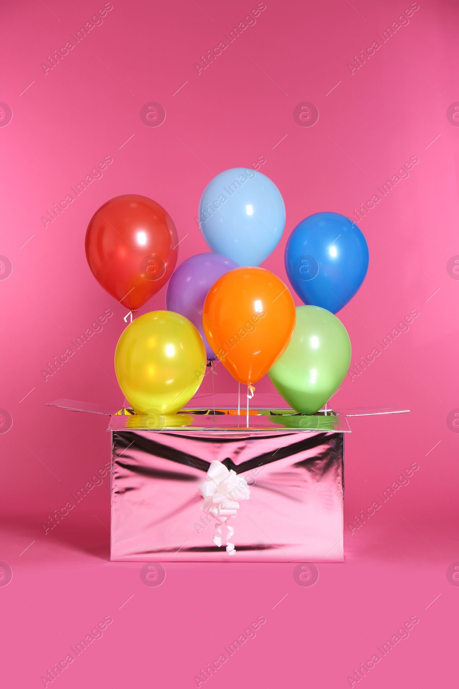 Photo of Gift box with bright air balloons on color background