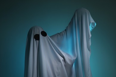 Creepy ghost. Woman covered with sheet on dark teal background