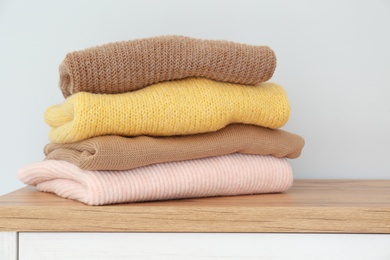 Photo of Stack of folded warm knitted sweaters on wooden table