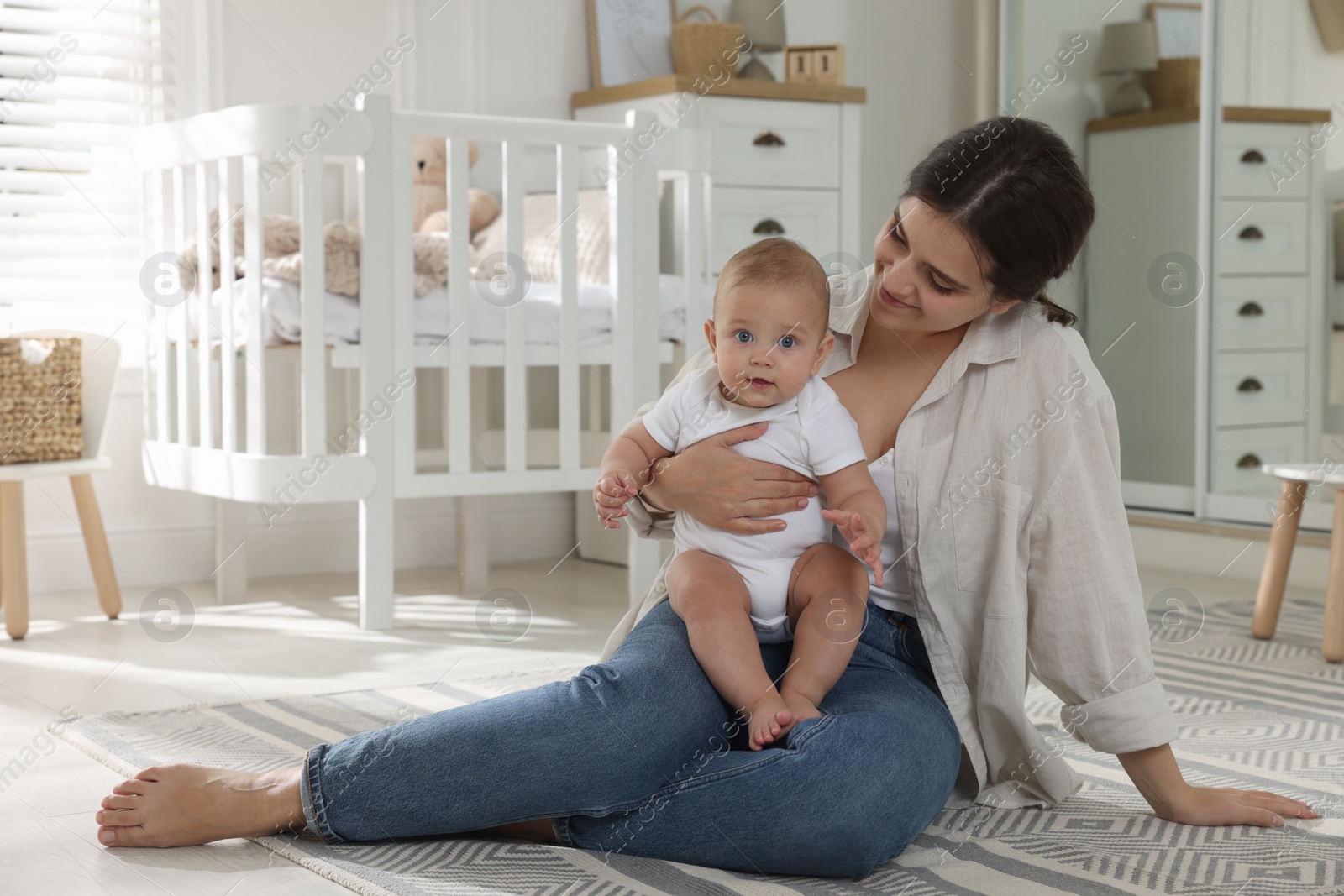 Photo of Happy young mother with her baby in nursery. Space for text