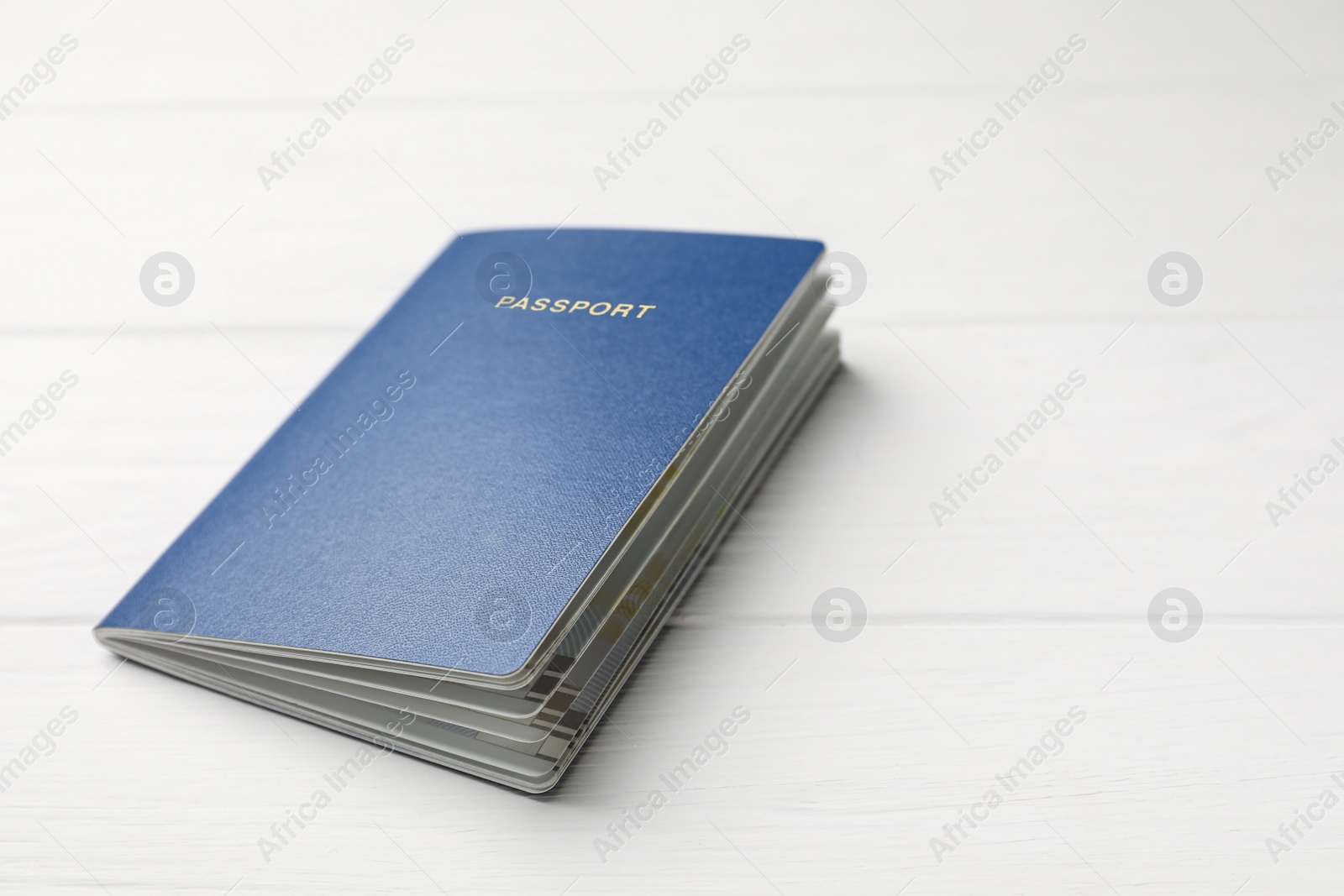 Photo of Blank blue passport on white wooden table, closeup. Space for text