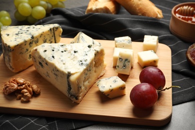 Photo of Board of delicious blue cheese with snacks on table