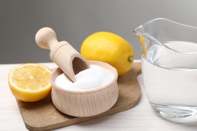 Photo of Baking soda, vinegar and lemons on white wooden table