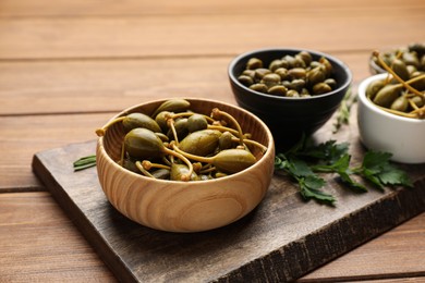 Photo of Tasty capers and parsley on wooden table