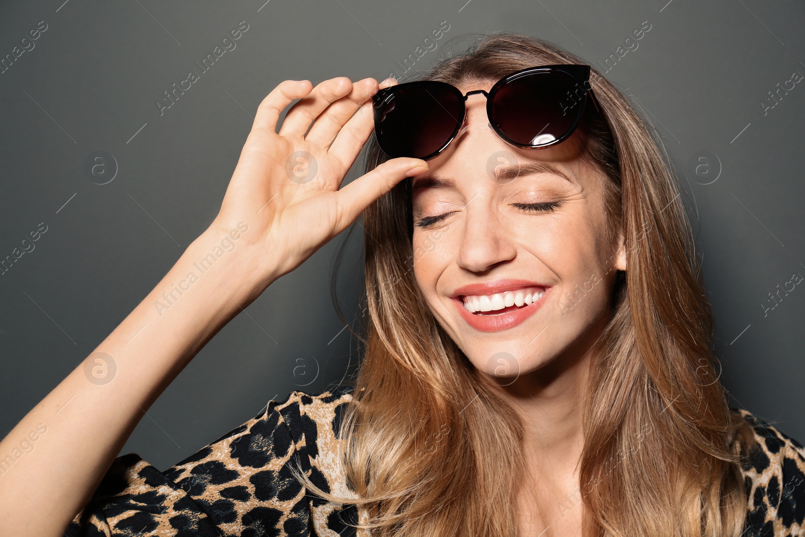 Photo of Young woman wearing stylish sunglasses on dark grey background