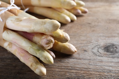 Photo of Bunch of fresh white asparagus on wooden table, closeup. Space for text