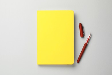 Photo of Yellow notebook and pen on gray background, flat lay