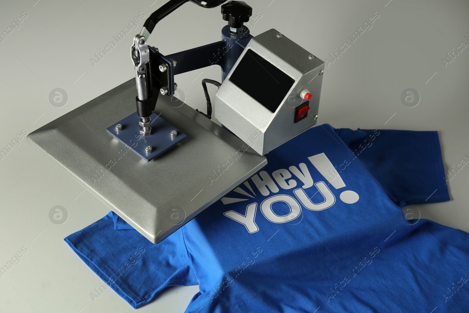 Photo of Printing logo. Heat press with blue t-shirt on white table