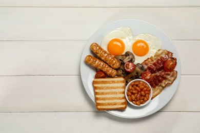Plate of fried eggs, sausages, mushrooms, beans, bacon and toast on white wooden table, top view with space for text. Traditional English breakfast