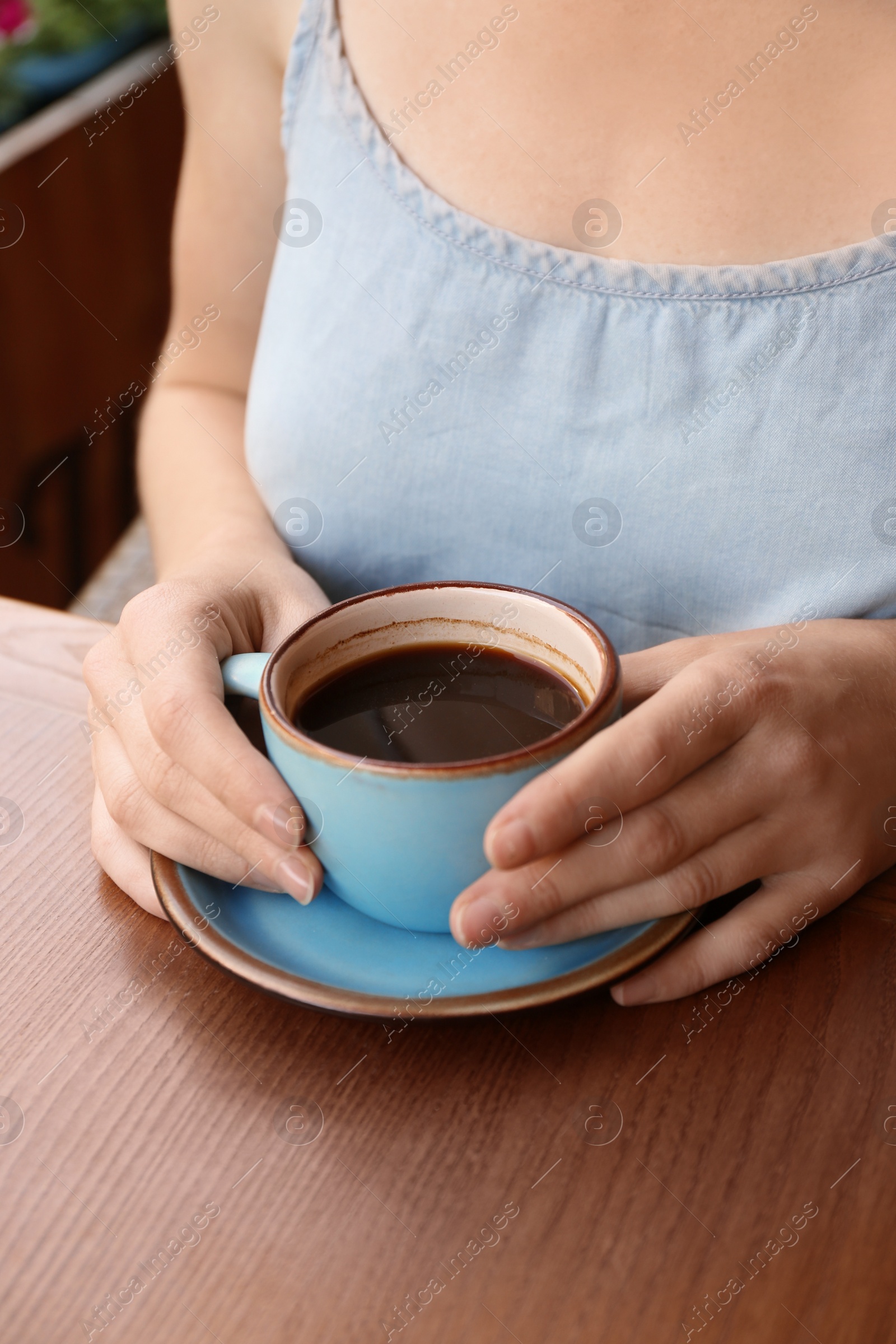 Photo of Woman with cup of fresh aromatic coffee at table, closeup