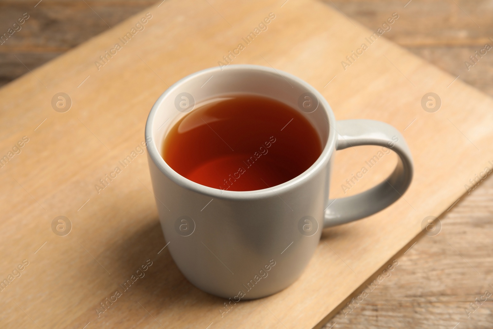 Photo of Cup of black tea on wooden board