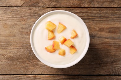 Photo of Delicious yogurt with fresh peach on wooden table, top view
