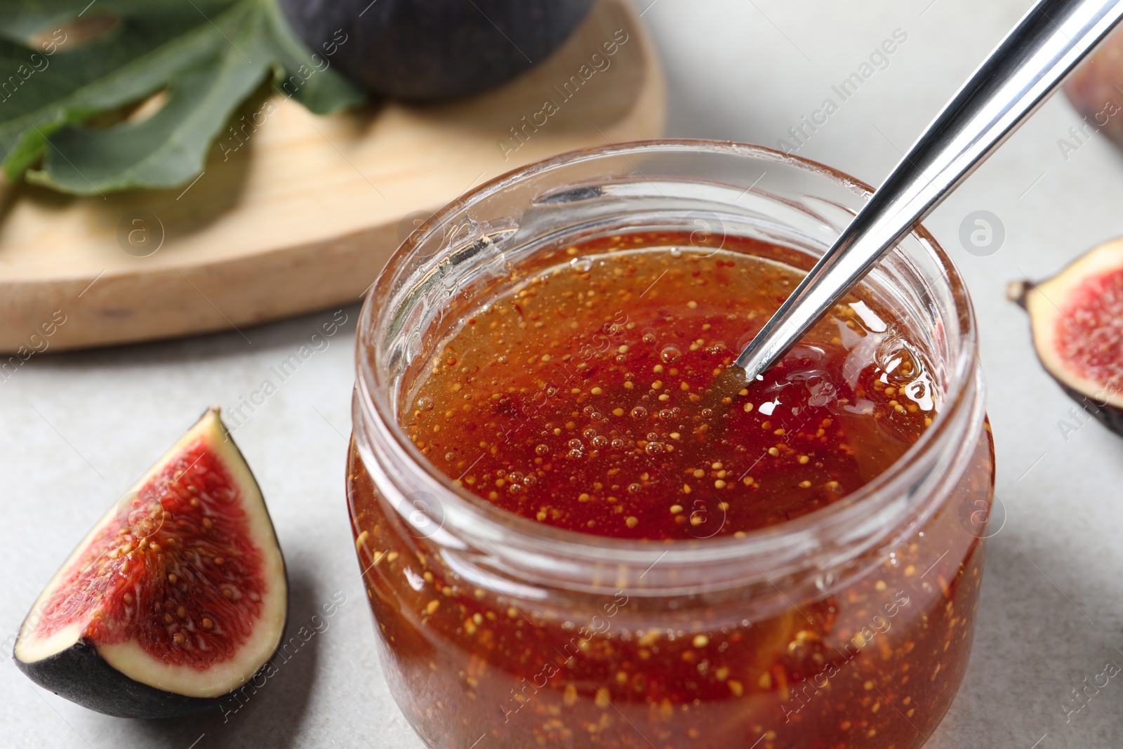 Photo of Jar with tasty fig jam and fresh fruits on white table, closeup