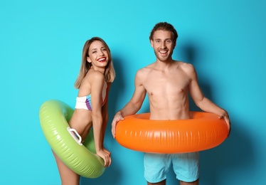 Photo of Happy young couple in beachwear with inflatable rings on color background