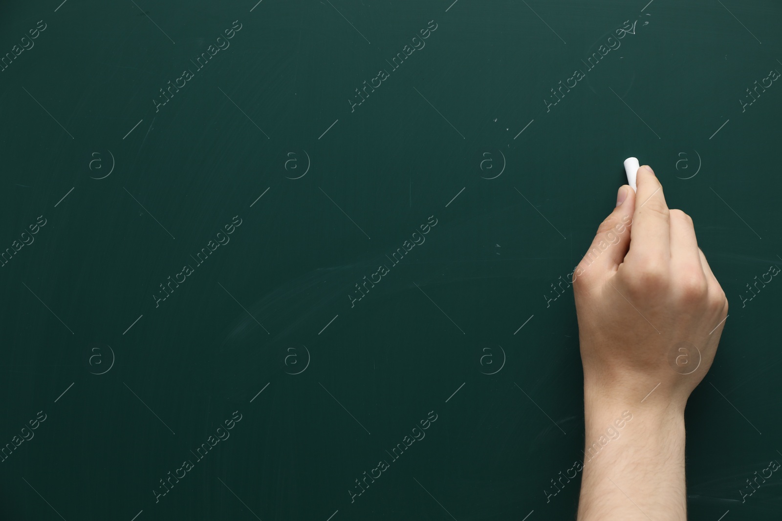 Photo of Teacher writing with chalk on green chalkboard, closeup. Space for text