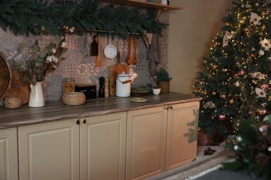 Stylish kitchen with festive decor and Christmas tree. Interior design