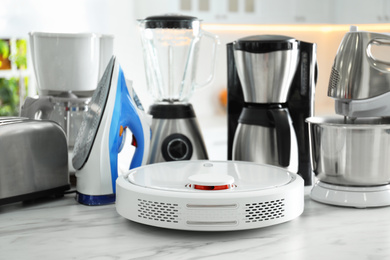 Photo of Set of modern home appliances in kitchen, focus on robotic vacuum cleaner