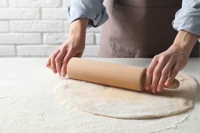 Photo of Woman rolling raw dough at table, closeup