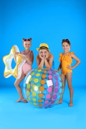 Photo of Cute little children in beachwear with inflatable toys on light blue background