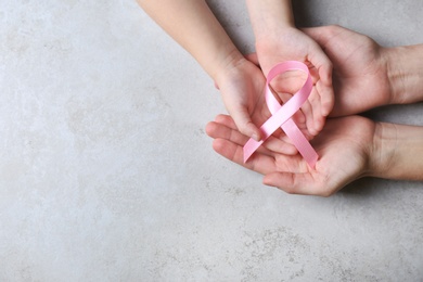 Woman and girl holding pink ribbon on grey background, top view with space for text. Breast cancer awareness