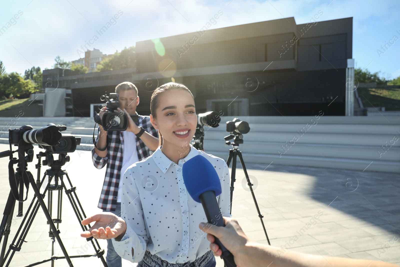 Photo of Professional journalist and operator with video camera taking interview outdoors