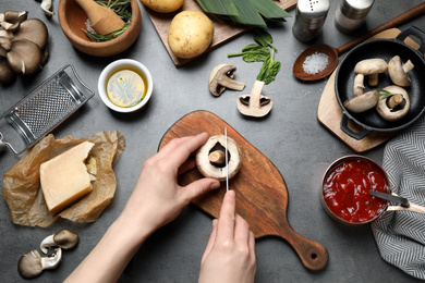 Photo of Woman cutting mushroom at grey table, top view. Healthy cooking