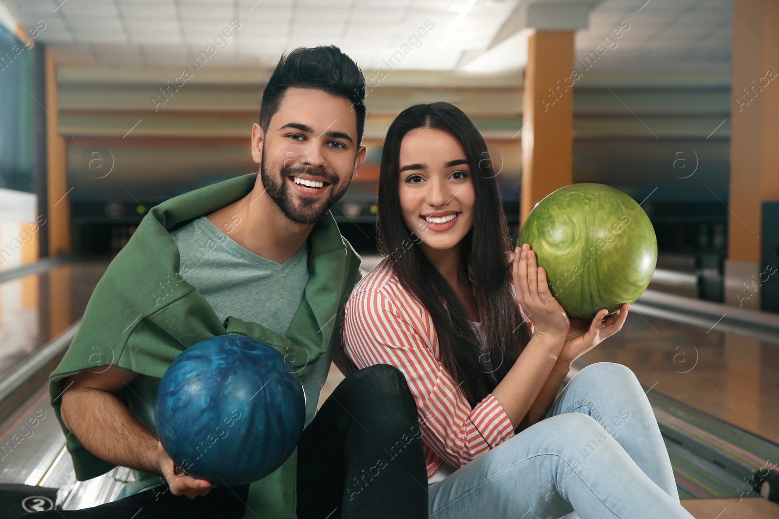 Photo of Happy young couple with balls in bowling club