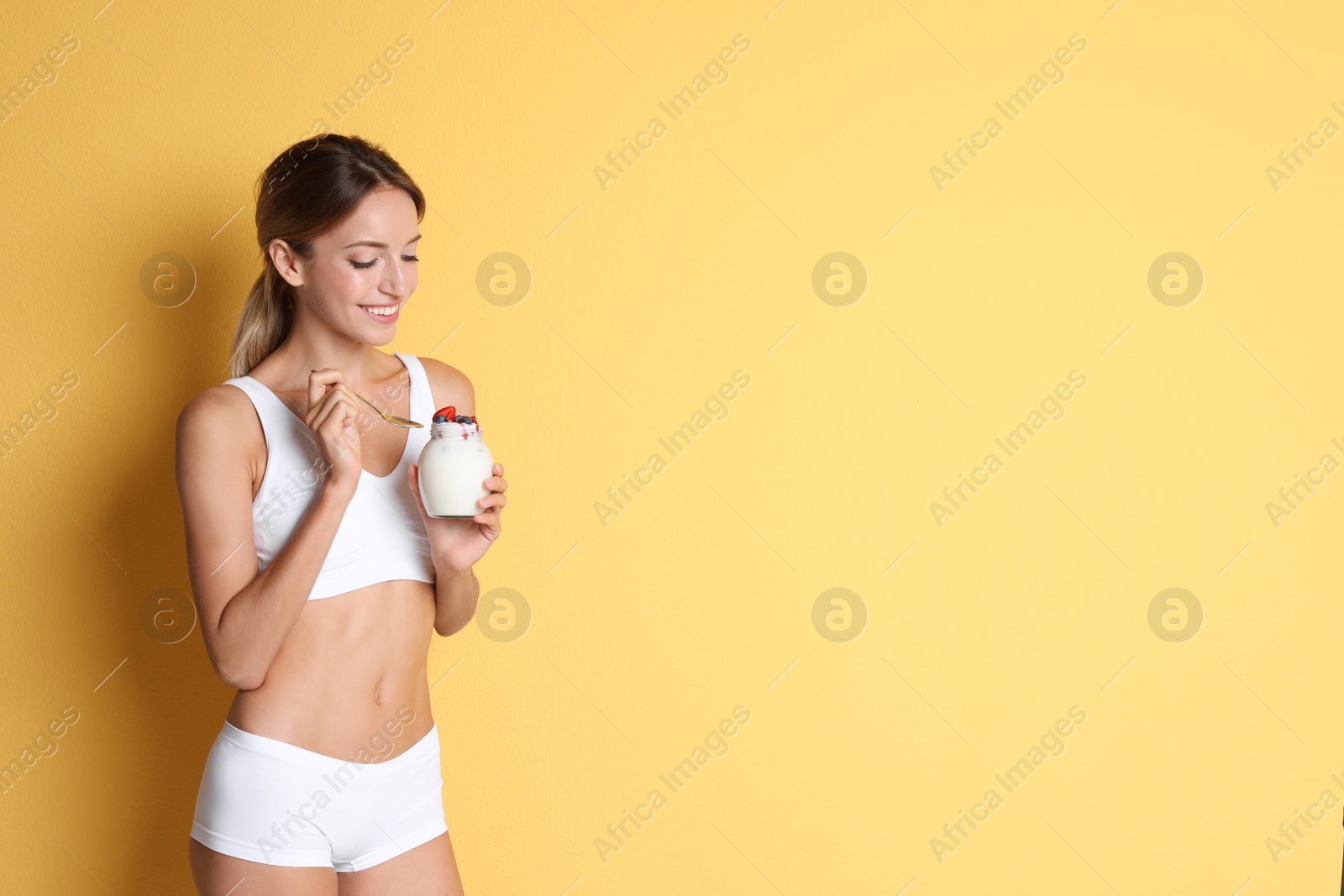 Photo of Happy slim woman in underwear with yogurt on color background. Weight loss diet