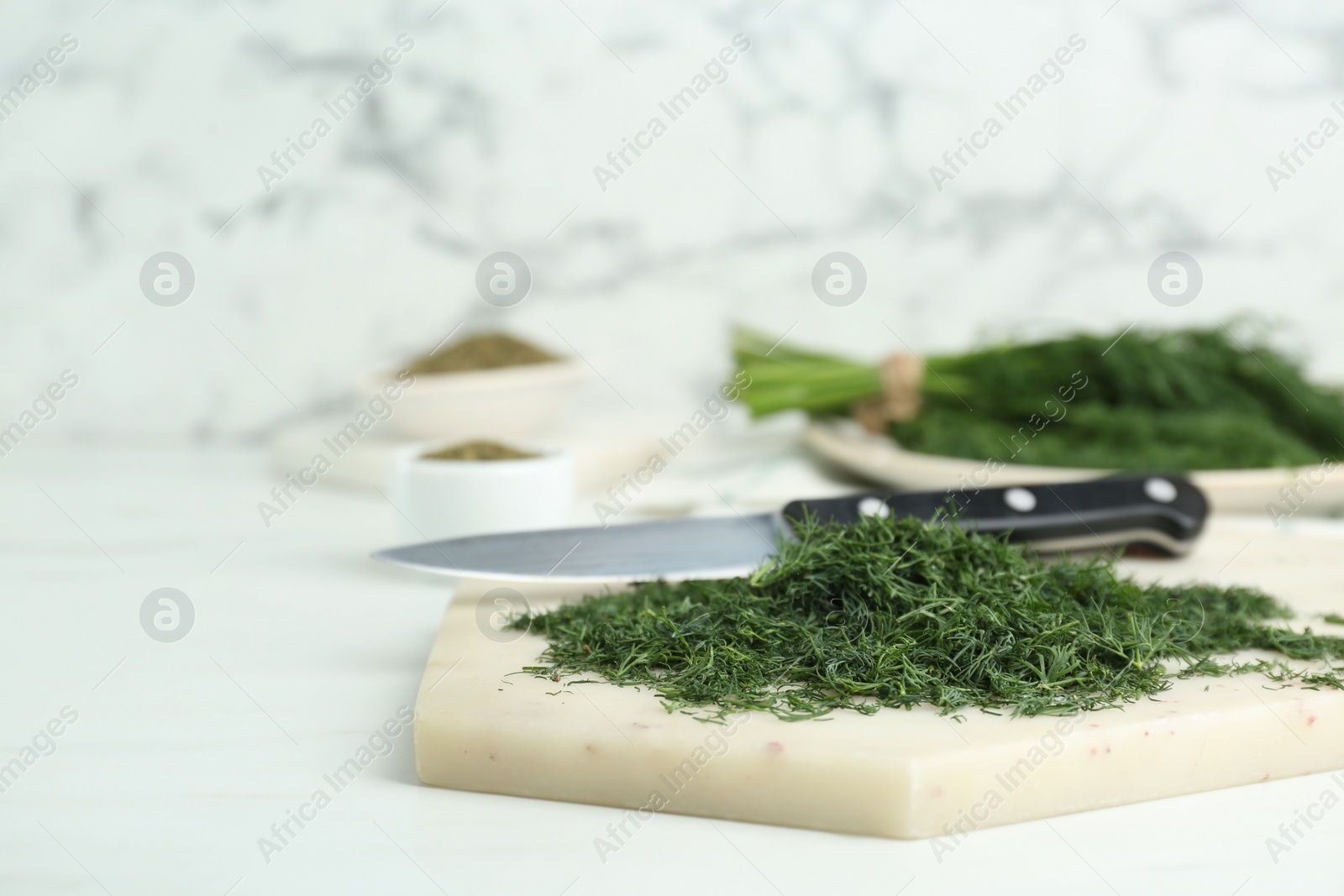 Photo of Fresh dill preparing for drying on white board near marble background. Space for text