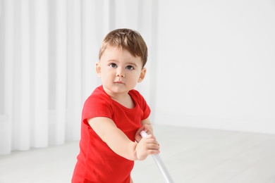 Photo of Cute baby playing with toy walker indoors