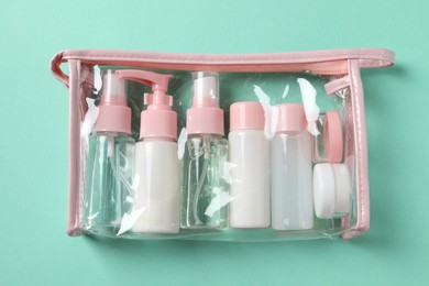 Photo of Cosmetic travel kit in plastic bag on turquoise background, top view. Bath accessories