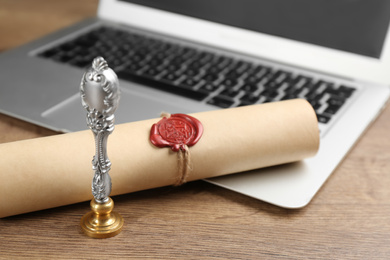 Photo of Notary's public pen and sealed document near laptop on wooden table